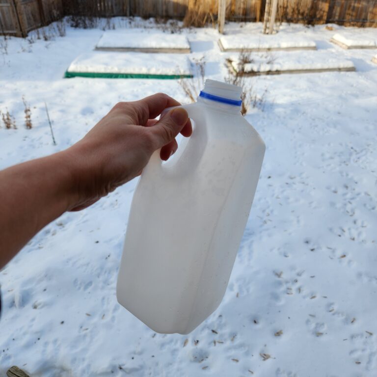 A hand holding an empty milk jug